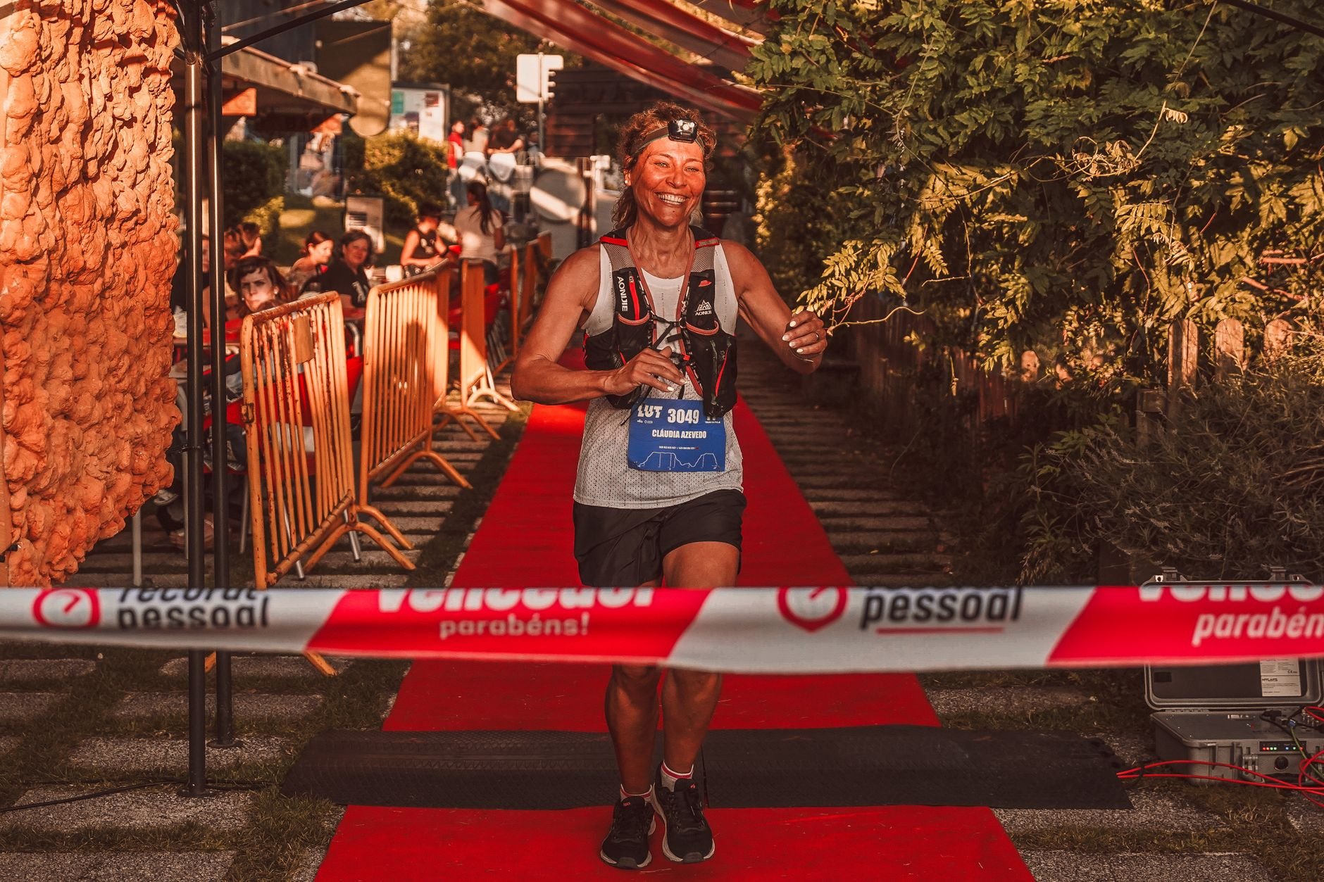 A runner crossing the finish line triumphantly, arms raised at an outdoor race