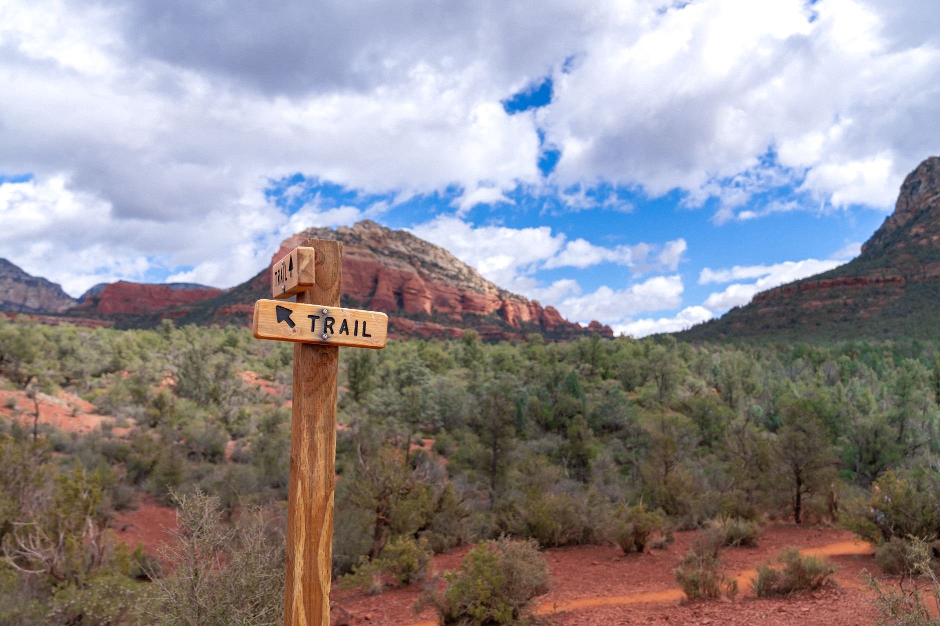 Wooden trail sign in Sedona's red rock landscape pointing runners to the trails